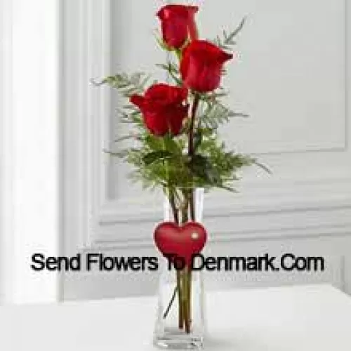 3 Red Roses In A Glass Vase Having A Small Heart Attached To It