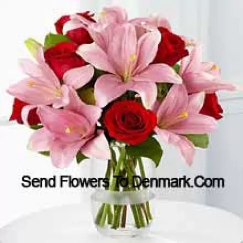 Roses rouges et lys roses avec des garnitures saisonnières dans un vase en verre